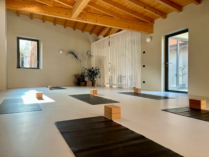 Omea Yoga a Como: tappetini neri e mattoncini in sughero sul pavimento, soffitto in travi di legno e tende bianche